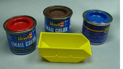 der unbemalte, gelbe Container neben 3 Revell-Farbdosen