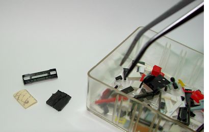 Frontstoßfänger und 2 Kleinteile neben einer unserer Ersatzteilkisten