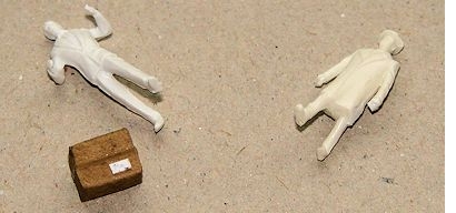 zwei unbemalte PREISER-Figuren neben einem Miniaturpaket