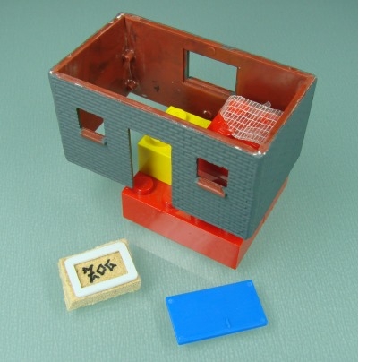 der Geräteschuppen, verschliffen und grau grundiert, davor Tür- und Fensterteile