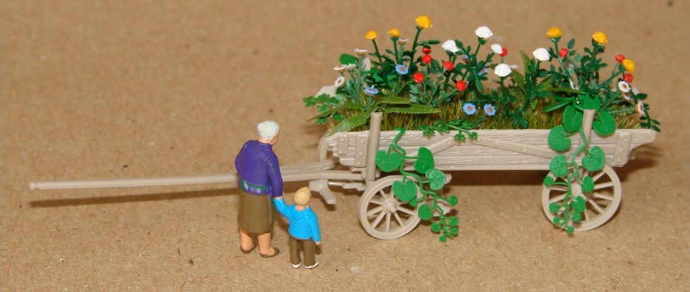 eine Großmutter und ihr Enkel stehen vor dem Blumenkarren und betrachten diesen