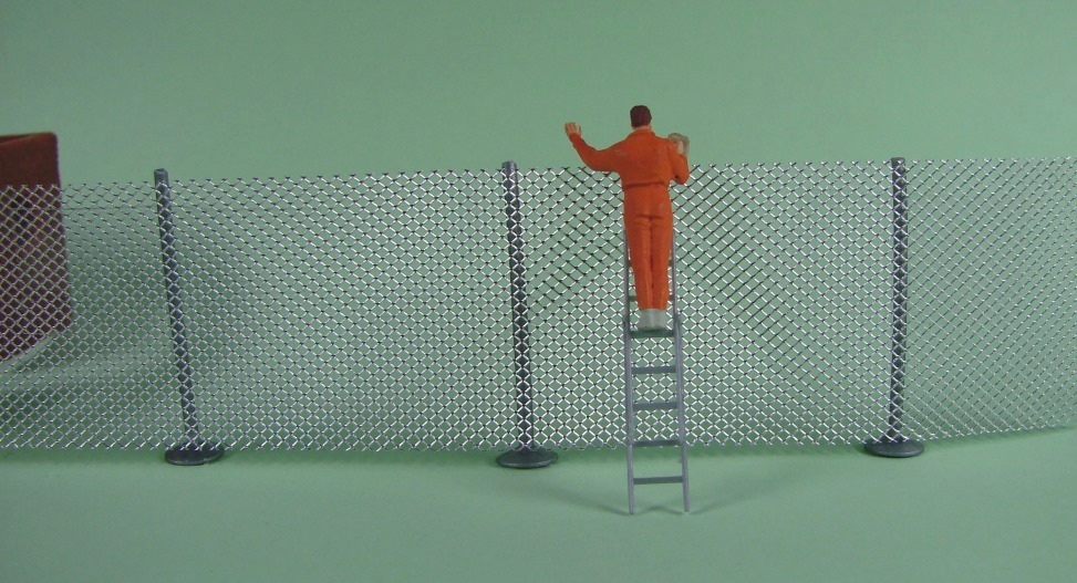 Mann auf Leiter, die am Maschendrahtzaun lehnt