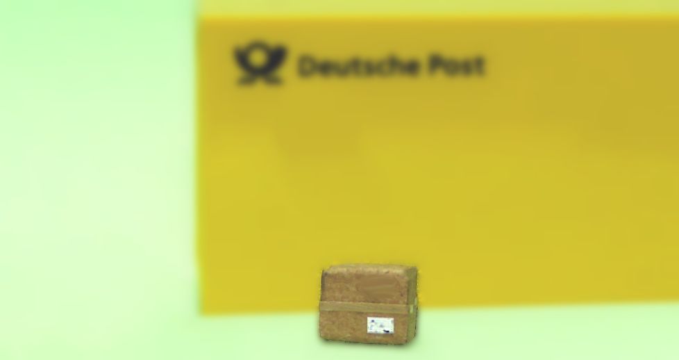 Miniaturpostpaket vor einer verschwommenen gelben Fläche mit 'Deutsche Post'-Aufschrift
