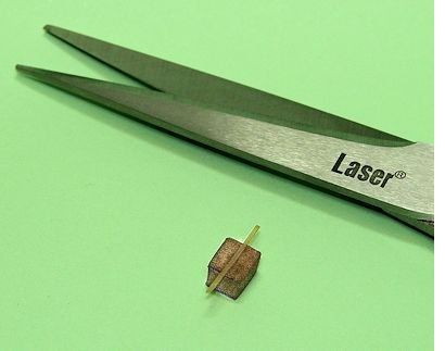 Schere liegt neben dem Minipaket, auf das ein hauchdünner Streifen Paketklebeband aufgebracht wurde